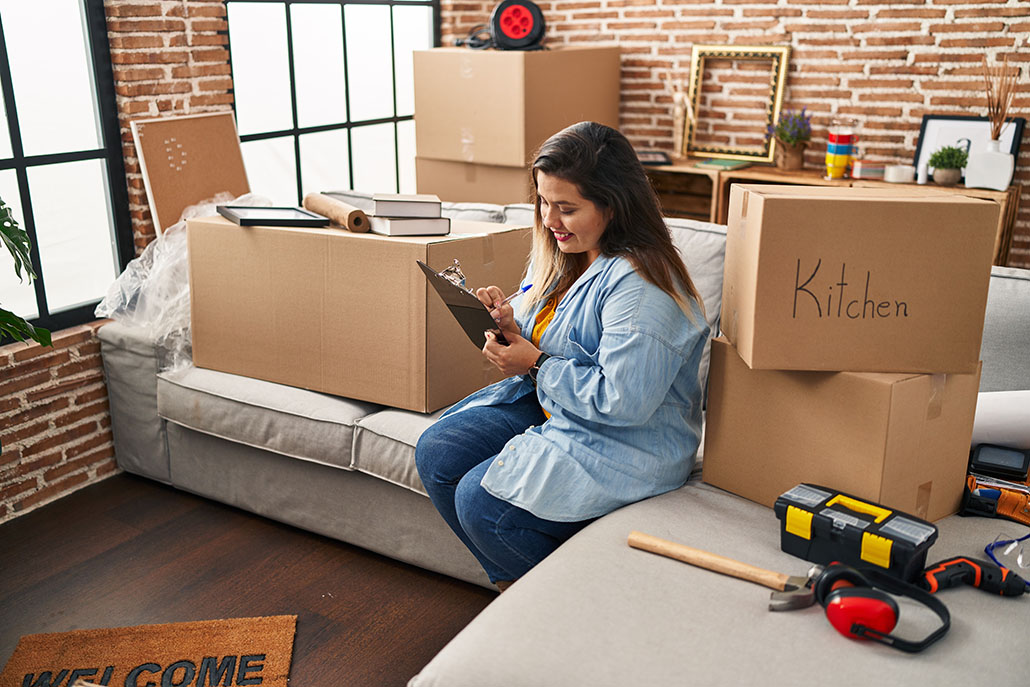 Woman making a checklist with moving boxes around her